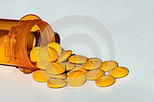 Yellow prescription pills spilled onto a table. Concept of opioid addiction and healthcare industry