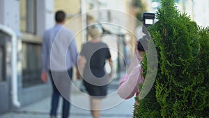 Yellow press journalist taking photo of elderly celebrity walking with young man