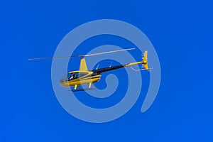 Yellow private helicopter in flight against the background of a