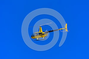 Yellow private helicopter in flight against the background of a