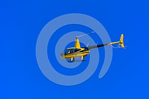 Yellow private helicopter in flight against the background of a