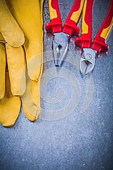 Yellow protective gloves pliers wire-cutter on metallic backgrou
