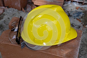 Yellow protective helmet on pile of red bricks