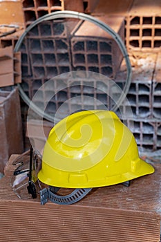 Yellow protective helmet on pile of red bricks photo