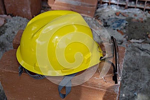 Yellow protective helmet on pile of red bricks photo