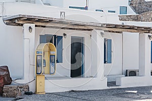 Yellow public telephone on a street in Hora Mykonos Town, Mykonos, Greece