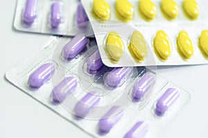 Yellow and purple blisters of pills on white background