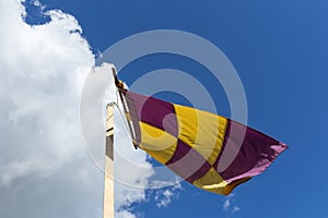 Yellow and purple flag on a banner swaying against the wind on a