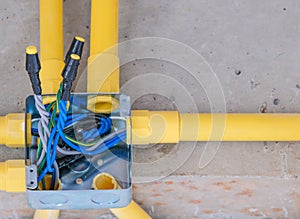yellow PVC tube eletric light system install square hub iron box on concrete raw wall for building in house site. fixing pipe for