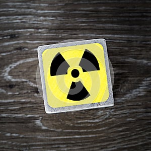 A yellow radiation warning symbol, sign or icon on a wooden background