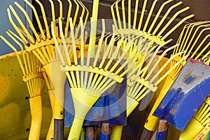 Yellow Rake and shovels for garden works stand vertically in a bright yellow barrel
