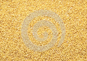 Yellow raw organic healthy bulgur grain seeds textured background.Macro