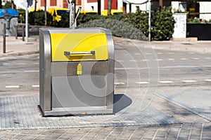 Yellow recycling container on a city street, inviting people to dispose of their plastic waste responsibly