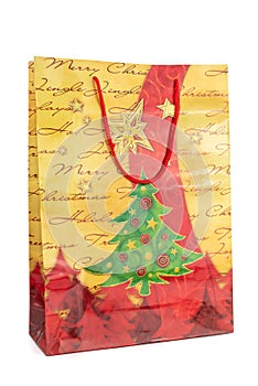 Yellow and red Christmas shopping bag made of paper decorated with a green tree on a white background. New year and gifts concept