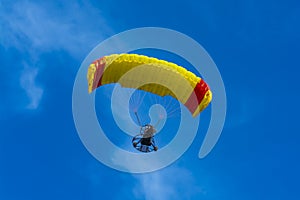 Yellow and red powered tandem para glider flying