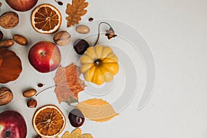 Yellow and red pumpkins on a light background with red apples, dry leaves, chestnuts. Autumn composition, fall