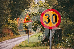 Yellow and red road traffic signs circular `speed limit 30` and triangular `Caution children`.