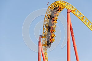 Yellow-red roller coaster from a trolley with rolling people rapidly going down