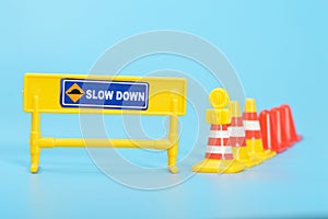 yellow and red safety cones with text SLOW DOWN. Reduce speed road sign