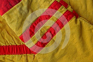 Yellow red striped fabric background from an old piece of clothing with a sleeve