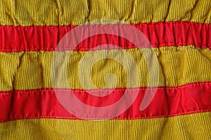 Yellow red striped fabric texture from an old piece of clothing with seams