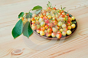 Yellow-red sweet cherry in a plate on a wooden table