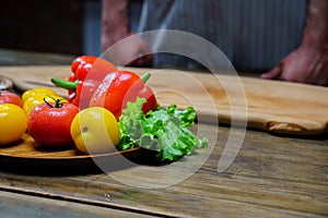 yellow and red tomatoes, lettuce and bell pepper with water drops. man in apron.