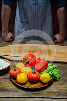 yellow and red tomatoes, lettuce and bell pepper with water drops. man in apron.