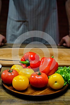 yellow and red tomatoes, lettuce and bell pepper with water drops. man in apron.