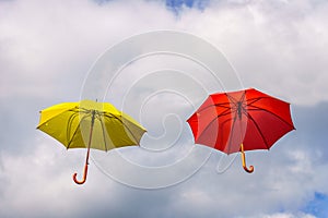 Yellow and red umbrella or parasols floating suspended in the air