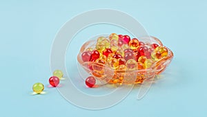 Yellow and red vitamin A, E, D, omega 3, cod-liver, fish, Evening primrose oil dietary supplement gel capsules in glass plate on