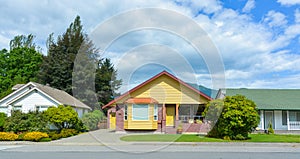 Yellow residential house with accurate lawn and concrete driveway to the garage