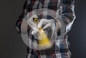 Yellow retractable tape measure tool in hands of repairman, closeup