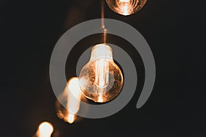 Yellow retro incandescent bulbs hang in the evening at a party. Light bulbs hanging on a wooden bridge at night