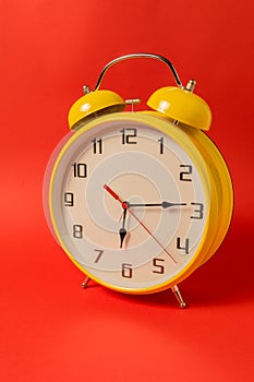 Yellow Retro style alarm clock with fifteen minutes past six o `clock