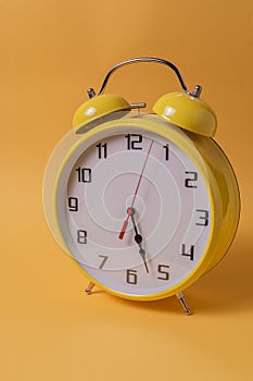 Yellow Retro style alarm clock over yellow background