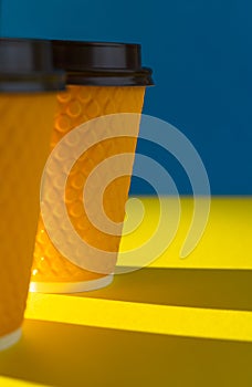 Yellow ribbed paper cup with plastic lid for takeaway beverage in fast food restaurants. A cup of coffee, cocoa, tea from a street