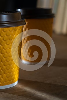 Yellow ribbed paper cup with plastic lid for takeaway beverage in fast food restaurants. A cup of coffee, cocoa, tea from a street