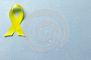 Yellow ribbon on a blue cement  background.World suicide prevention day.