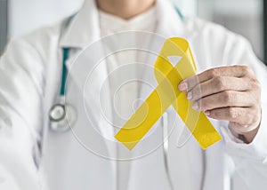 Yellow ribbon symbolic color for Sarcoma Bone cancer awareness and suicide prevention in doctorÃ¢â¬â¢s hand photo