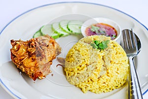 Yellow rice with fried chicken on dish.