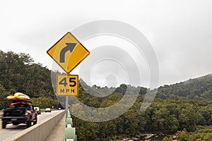 A yellow right curve ahead traffic sign on Sandy Hook bridge over Potomac River.