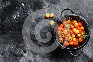 Yellow ripe cherries in a colander. Black background. Top view. Copy space