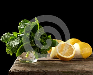 Yellow ripe lemon and a bunch of fresh green mint on a wooden board