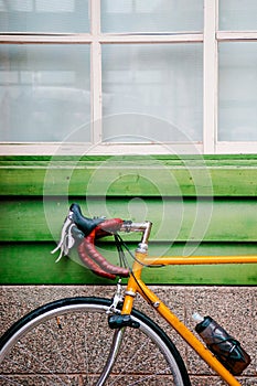 Yellow Road bicycles parking against green wooden wall.