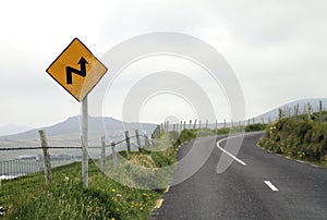 Yellow road sign announcing a dangerous curve ahead