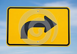Yellow road sign with a black right-turn arrow. Rectangular shape with