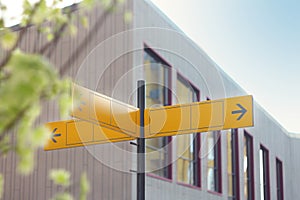 Yellow road sign or blank road signs showing direction against a building