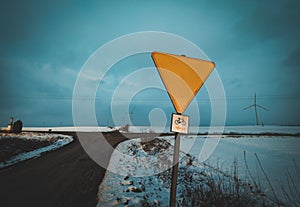 yellow road sign at crossroads in winter