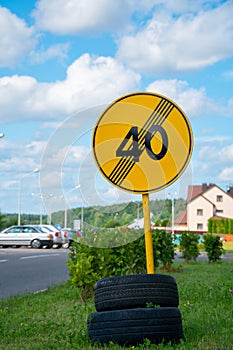 Yellow road sign fixed on tires near the road